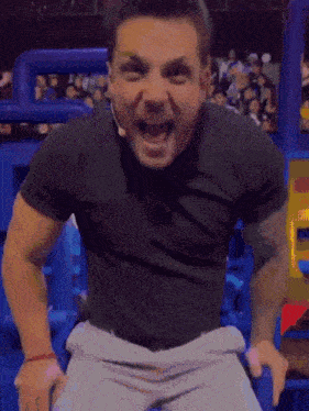 a man wearing a black shirt and a microphone screams in front of a crowd