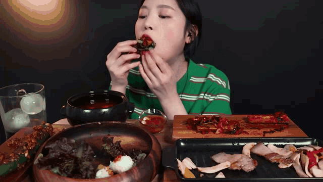 a woman is sitting at a table eating a piece of food