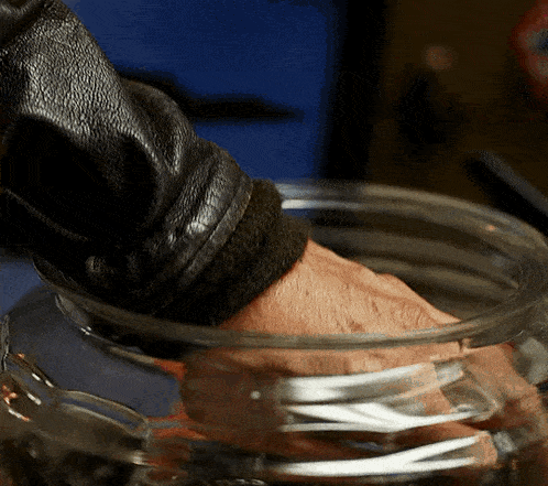 a close up of a person 's hand holding a glass bowl