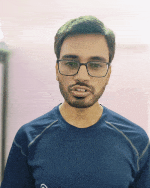 a man with glasses and a beard is wearing a blue shirt with the letter c on it