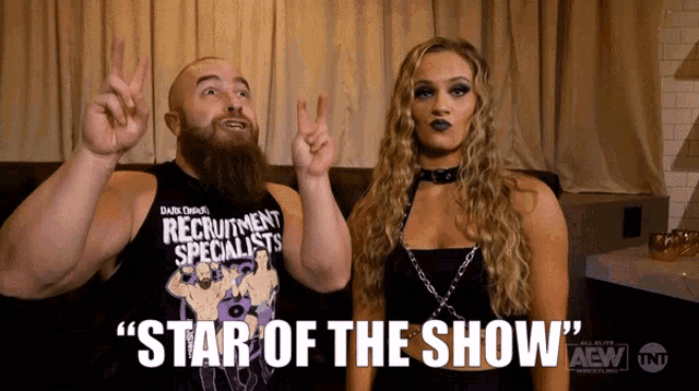a man and a woman are standing next to each other and the man is wearing a shirt that says " star of the show "