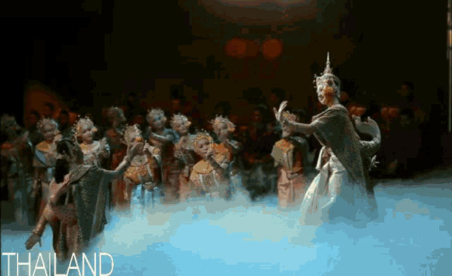 a group of people are dancing in front of a crowd and the word thailand is on the bottom right