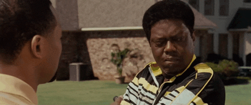 a man wearing a black and yellow shirt talks to another man