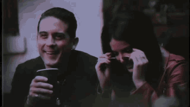 a man and a woman are sitting next to each other and laughing .