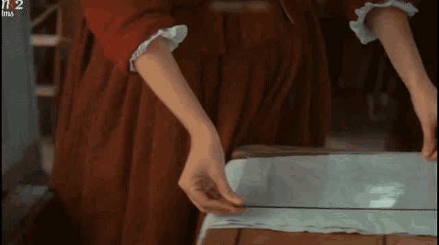 a woman in a red dress is measuring a piece of cloth in front of a sign that says n12