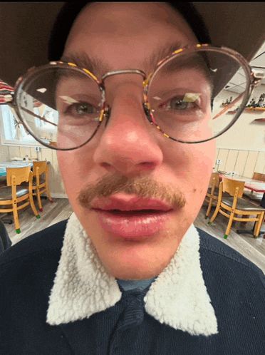 a man with glasses and a mustache looks at the camera with his mouth open