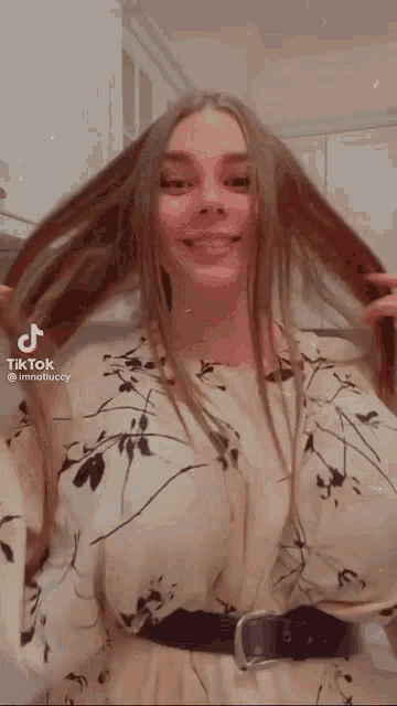 a woman with long hair is standing in a kitchen holding her hair .