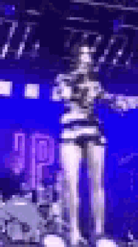 a woman in a striped dress is standing on a stage holding a microphone .