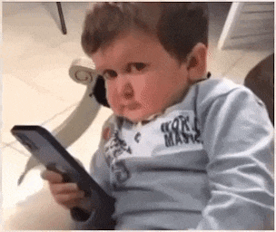 a little boy is sitting in a chair holding a cell phone in his hand .