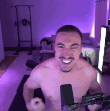 a shirtless man is smiling in front of a microphone