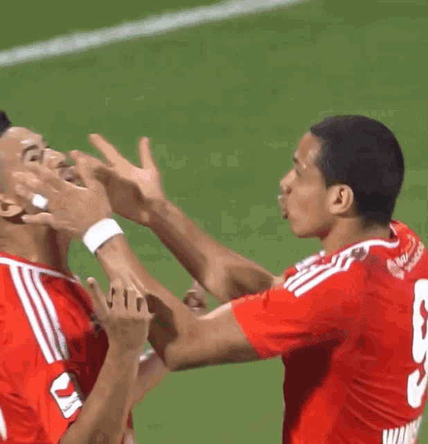 two soccer players wearing red jerseys one with the number 9 on it