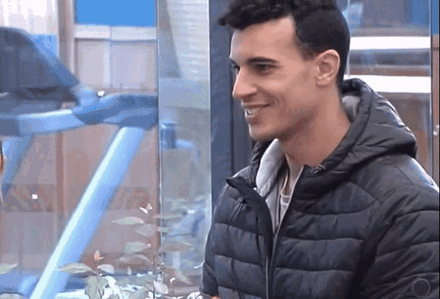 a man in a black jacket is smiling and looking out a window