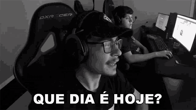 a man wearing headphones and a hat is sitting in front of a computer and says que dia e hoje ?