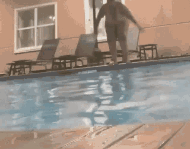 a man is jumping into a swimming pool in front of a hotel