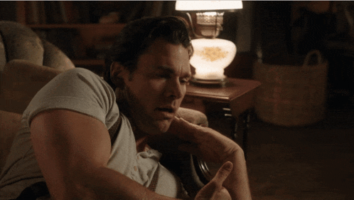 a man sits in a chair with his hand on his elbow
