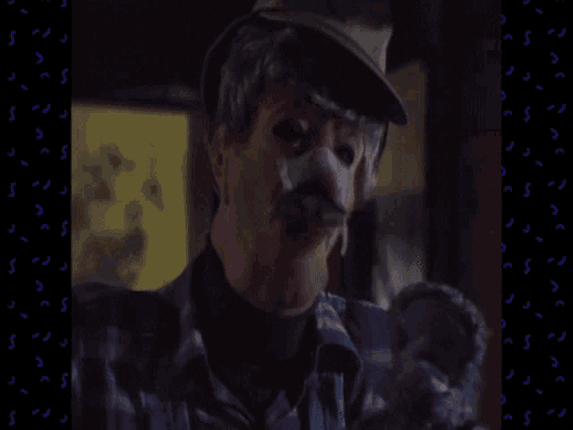a man wearing a clown mask and a hat is holding a stuffed animal