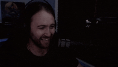 a man wearing headphones is sitting in a dark room with his hand on his forehead