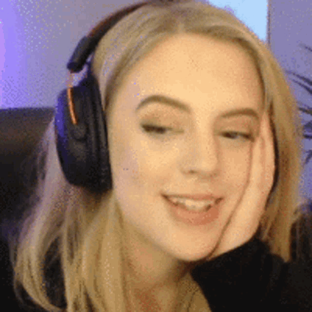 a close up of a woman wearing headphones with her hand on her face