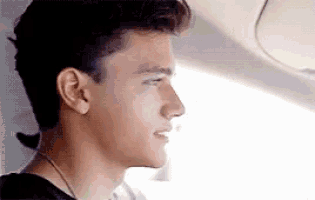 a young man is sitting in the back seat of a car looking out the window .
