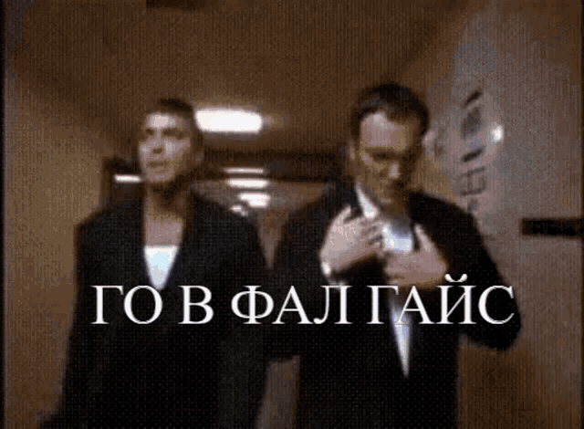 two men in suits are walking down a hallway with the words " go in fal taic " written on the bottom