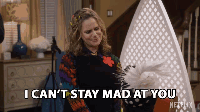 a woman holding a fan with the words i can 't stay mad at you below her