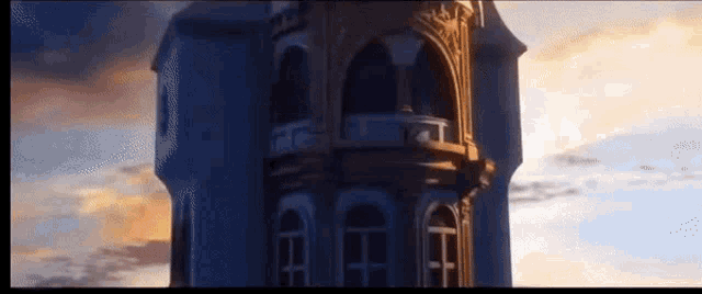 a very tall building with a balcony and a sunset in the background