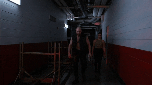 a man and a woman are walking down a hallway with red lights
