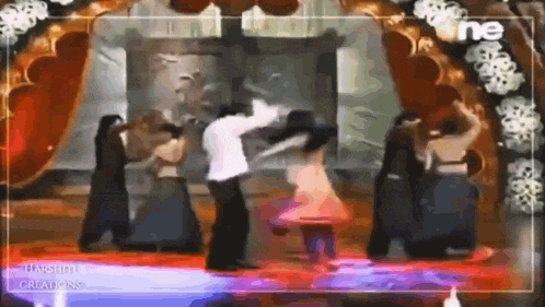 a group of people are dancing on a stage in front of a curtain .