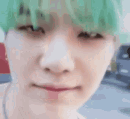 a close up of a person 's face with green hair and a car in the background