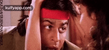 a man wearing a red headband is looking at another man in a mirror .