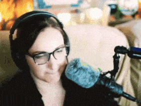 a woman wearing headphones and glasses sits in front of a microphone that says intercom on it