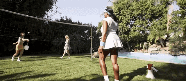 a woman in a tennis skirt stands in front of a net