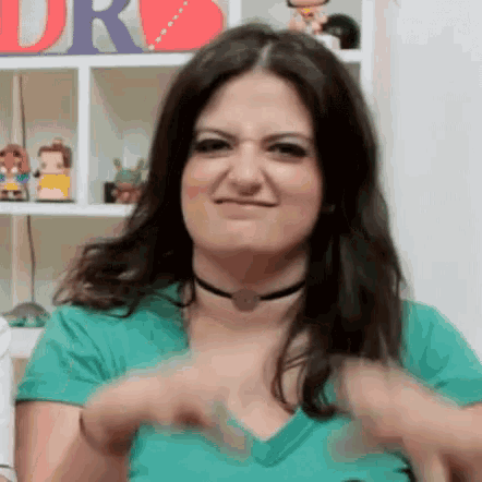 a woman wearing a choker and a green shirt is making a face .