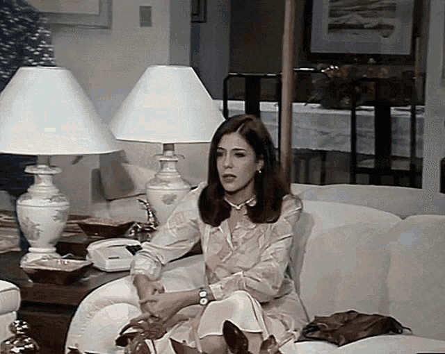 a woman sits on a white couch with two lamps