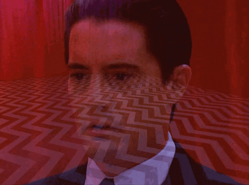 a man in a suit and tie is standing in front of a red chevron patterned floor