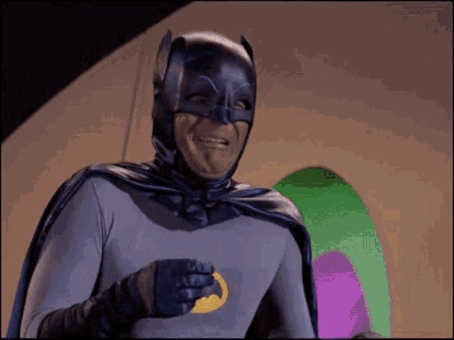 a man dressed as batman is holding a coin