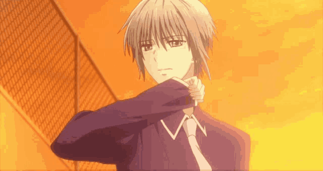 a man in a purple shirt and tie is covering his face with his hand
