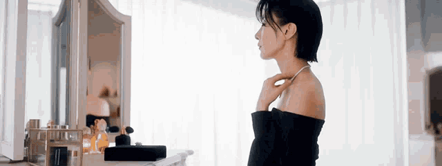 a woman is standing in front of a mirror and looking at herself .
