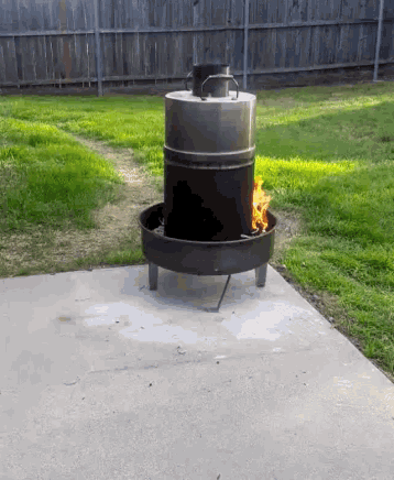 a fire pit in a backyard with a barrel in the middle