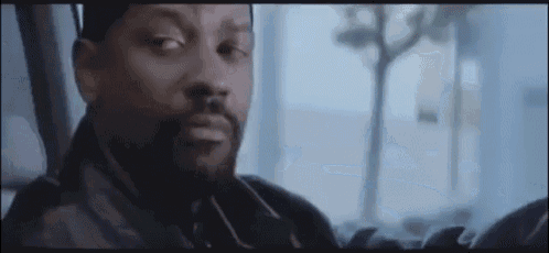 a man with a beard is sitting in a car looking out the window .