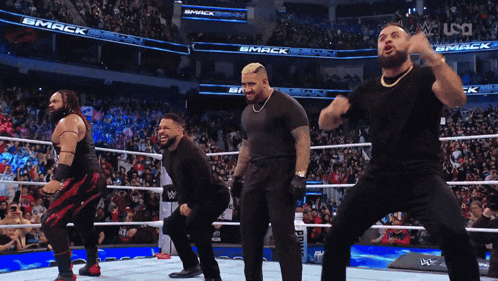 a group of men are dancing in a wrestling ring with the word smack on the jumbo tron