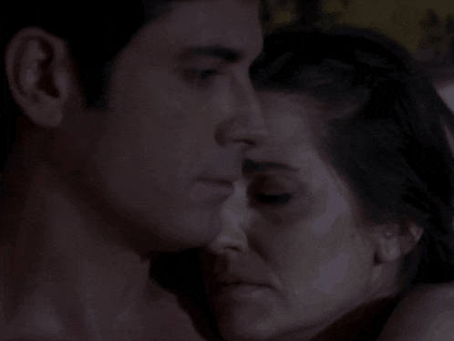 a man kisses a woman on the forehead in the dark