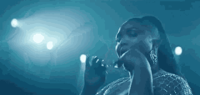 a woman is singing into a microphone on a stage in front of a blue background .