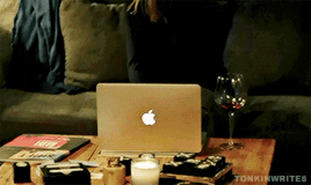 a woman sits on a couch with an apple laptop