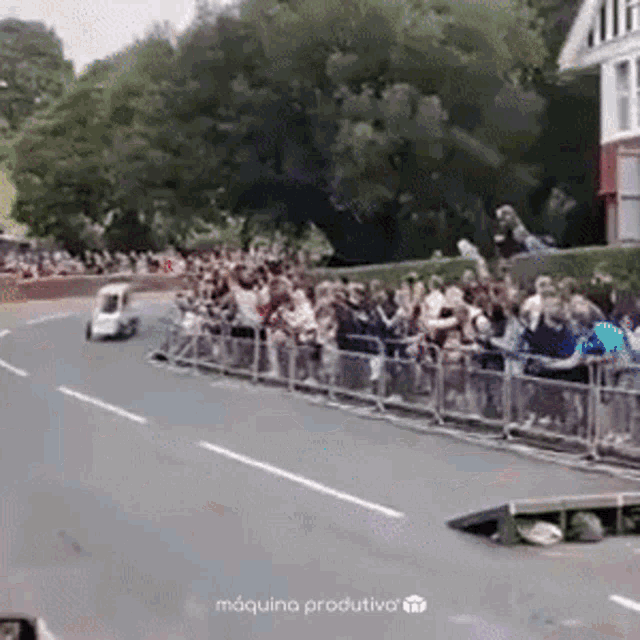 a car is driving down a road with a crowd of people watching .