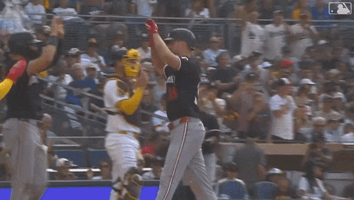 a group of baseball players are standing on a field holding their bats in the air .