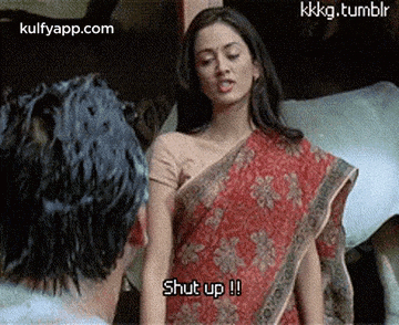 a woman in a red saree is standing next to a man and says shut up .