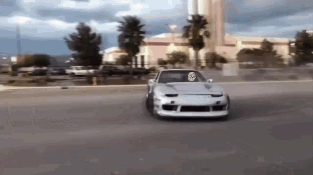 a white car with a skull on the front is driving down a street .