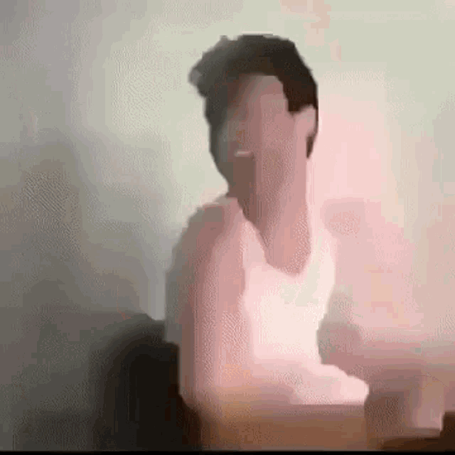 a man in a white tank top is sitting at a table with his arm outstretched .