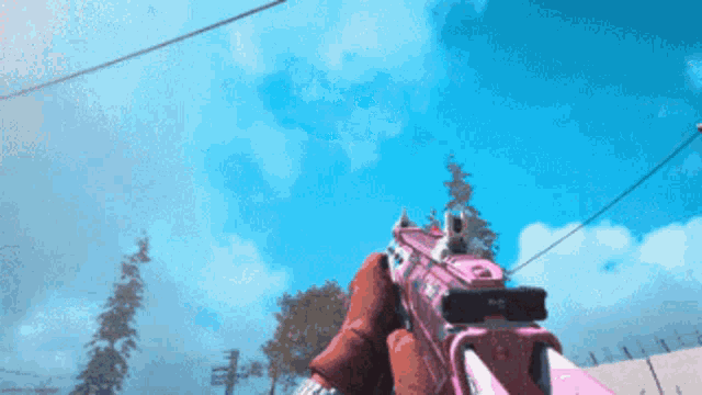 a person is holding a pink gun in front of a blue sky ..